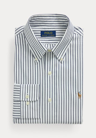 Összehajtott fehér ing tengerészkék függőleges csíkokkal, patentos gallérral és hímzett Polo Ralph Lauren logóval a mellkason.