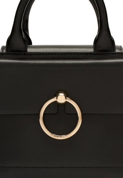 Sac à main en cuir noir au design structuré, avec un rabat avant, des accessoires circulaires en or, et une texture lisse et élégante.