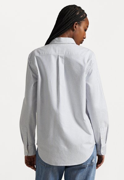 Camisa de rayas azul claro y blanca de manga larga con corte recto, pliegue en la parte posterior, puños abotonados y dobladillo redondeado, hecha de tela tejida.