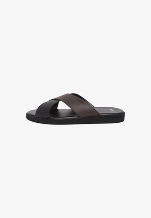 Brown and black slide sandal with crossed straps, flat sole, and logo on the insole. Made from synthetic materials, featuring smooth texture.