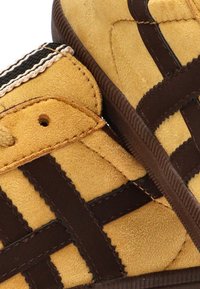 Zapatillas altas de ante en amarillo y marrón, con un diseño de cinta en contraste, parte superior texturizada y acentos de textil.