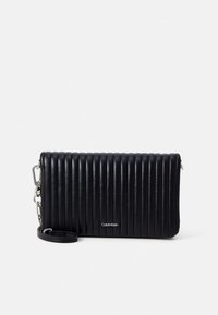 Svart quilte skinnclutch med vertikale ribber, avtakbar stropp og sølvfarget metallbeslag. Har en logo foran. Kompakt og strukturert design.