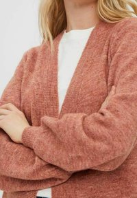 Kardigan růžové barvy vyrobený z měkké texturované látky. Má výstřih do V, spadená ramena a žebrované manžety. Lehký a útulný design.