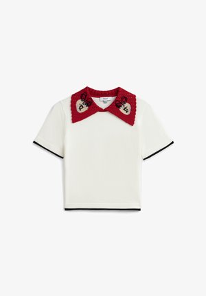 Bílý krátký rukáv s černým lemováním a velkým červeným háčkovaným límcem s béžovými srdíčky a černou výšivkou motýla.