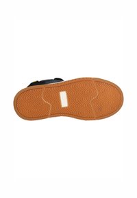 Semelle de chaussure avec une texture ondulée en caoutchouc orange, dotée d'une tache centrale blanche. Section supérieure noire visible au niveau du talon.