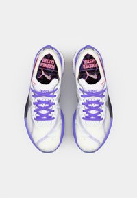 Des chaussures de sport blanches avec des accents violets, présentant un dessus à motifs, des lacets plats et une semelle texturée. "DEVIATE" imprimé sur le côté.
