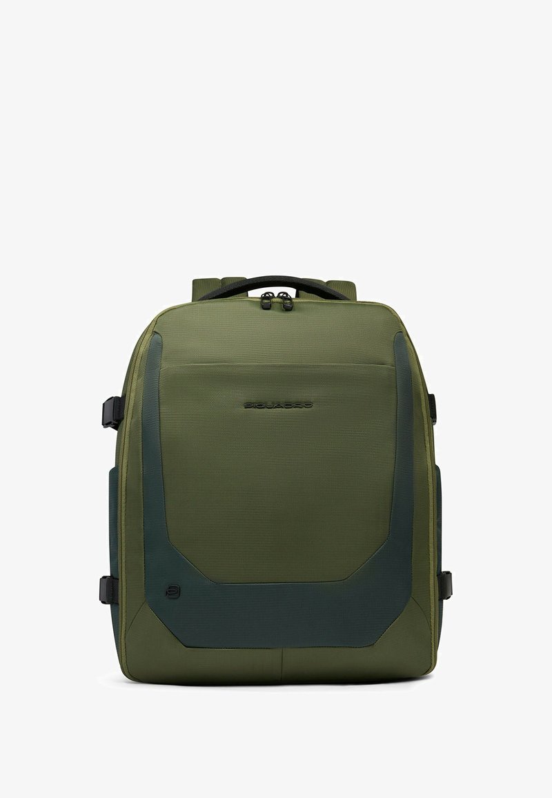 Mochila verde oliva con tela texturizada, respaldo acolchado y detalles laterales. Cuenta con dos asas superiores y correas de hombro ajustables.