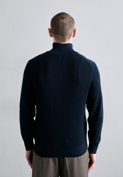 Navy-blaues geripptes Strickshirt mit hohem Kragen, taillierten Ärmeln und leichtem Stretch. Glatte Textur und minimale Nähte.