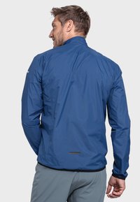Leichte blaue Jacke mit hohem Kragen, langen Ärmeln, Reißverschluss und reflektierenden Akzenten auf der Rückseite, aus glattem, wasserabweisendem Material.