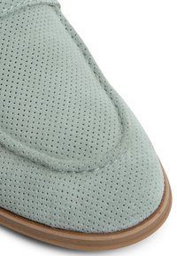 Light blue suede shoe with perforated texture, almond-shaped toe, contrasting stitching, and a brown rubber sole.