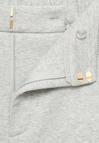 Tessuto grigio con una consistenza morbida, dotato di una tasca con zip, chiusura a bottone in plastica e dettagli in hardware dorato.