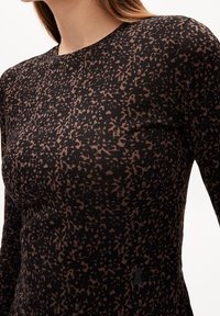Schwarzes Oberteil mit einem abstrakten braunen Muster, enganliegendem Schnitt, rundem Halsausschnitt und weichem Material, ideal für Freizeitkleidung.