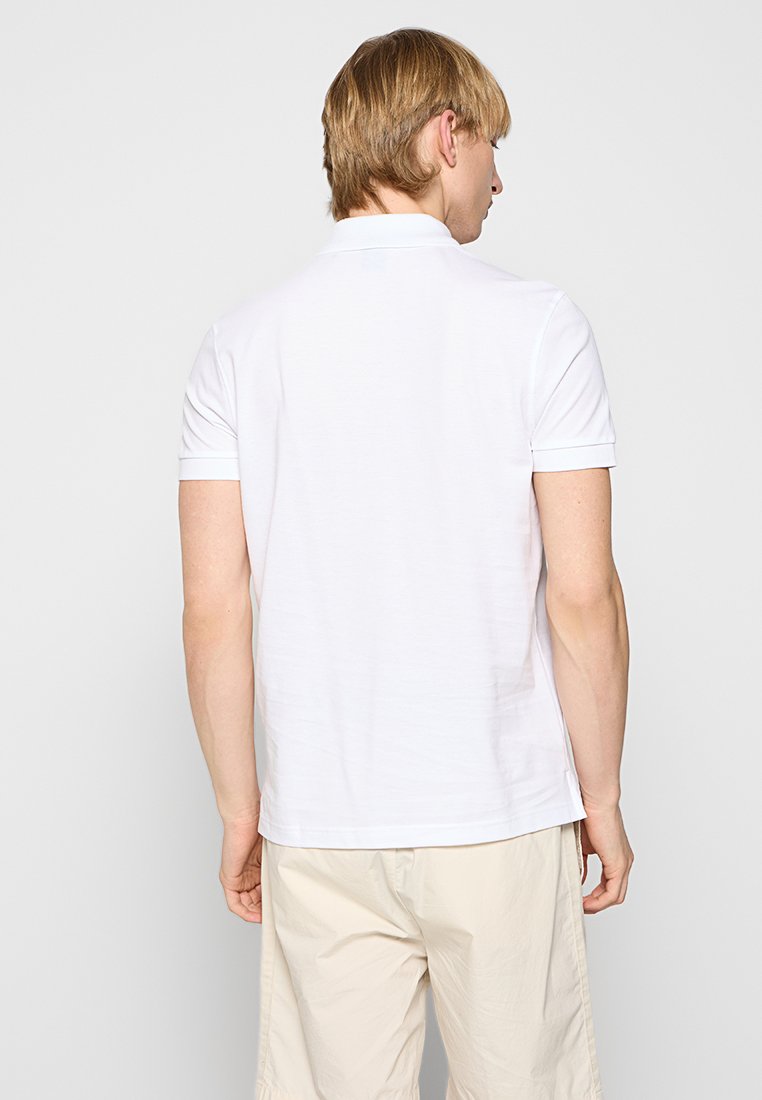 Polo-shirt en coton blanc à manches courtes, col sans couture et design simple et épuré. Finition avec un ourlet droit et sans embellissements.