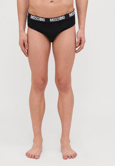 Boxers noirs Moschino avec une ceinture logo blanche. Le design présente une coupe ajustée et des coutures minimales, fabriqués dans un tissu lisse.