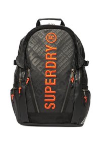 Czarny plecak z wytłoczonym wzorem "SUPERDRY", jasnopomarańczowym logo, wieloma kieszeniami na zamek błyskawiczny i regulowanymi paskami na ramiona.