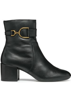 Bota de piel negra hasta el tobillo con tacón bloque y hebilla decorativa dorada en el lateral, acabado liso y diseño de punta redonda.