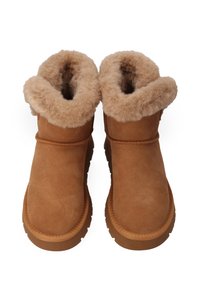 Pár hnědých kotníkových bot s hustou, načechranou kožešinovou podšívkou a gumovými podrážkami, navržených pro pohodlí a teplo v chladném počasí.