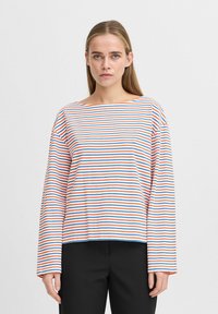 Haut à manches longues rayé en blanc avec des rayures horizontales rouges et bleues. Présente un décolleté large et une coupe décontractée. Le matériau semble doux et léger.