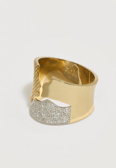 Large bague en or avec une bande texturée torsadée et un accent en diamants pavés incurvés sur un côté, présentée sur un fond blanc.