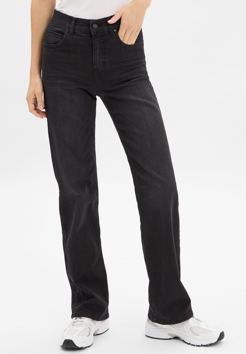 Jeans in denim nero con taglio dritto, vita alta, tasche frontali e chiusura con bottone, indossati con scarpe sportive bianche.