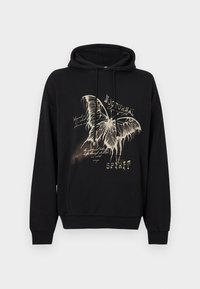 Juodas džemperis su gaubtu, puoštas dideliu, detaliu kreminės spalvos drugelio grafiku ir tekstu, priekine kanguros kišene bei ribotomis rankogaliais ir apačia.