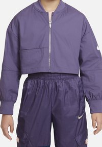 Purple cropped jacket with a zip front, ribbed collar, and a patch pocket. Paired with purple, textured elastic waist shorts featuring side pockets.
