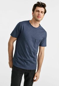 Granatowa koszulka z krótkim rękawem i okrągłym dekoltem, z małą kieszonką na piersi, wykonana z teksturowanej bawełny. Luźny krój z prostym dołem.