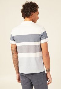 T-paita lyhyillä hihoilla, jossa on vaaleanharmaita, tummanharmaita ja valkoisia vaakasuoria raidoituksia. Puuvillamateriaalia ja pyöreä kaula-aukko.