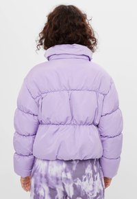 Fioletowa kurtka puchowa z wysokim kołnierzem i elastycznym pasem, z pikowanym wzorem i marszczonymi rękawami dla lepszej izolacji.