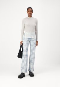 Lys grå ribbet langermet topp, sammen med mønstrede lys blå flagrende jeans. Svart vevet håndveske og kraftige svarte plattformsko.