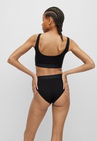 Black cotton bralette and high-waist underwear set. The bralette features wide straps and a band, while the panties have a smooth waistband.
