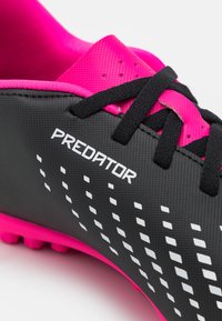 Scarpini da calcio neri con superficie texturizzata, dettagli rosa, logo "PREDATOR" bianco e motivo a pois. Presentano lacci neri e colletto imbottito.