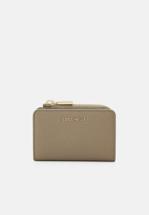 Portafoglio in pelle beige con finitura testurizzata, dotato di zip dorata e logo impresso sulla parte anteriore, design rettangolare compatto.
