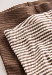 Brunt ribbet stof kombineret med et cremefarvet og brunt stribet mønster. Blød tekstur, der viser forskellige stoffinish og farver.