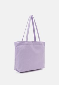 Sac fourre-tout en toile violette avec deux longues anses, forme rectangulaire, texture lisse, sans motifs visibles ni détails métalliques.