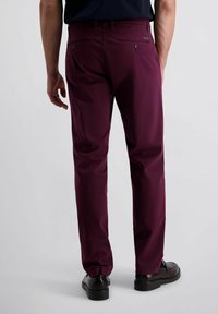 Bordeaux broeken van soepel materiaal hebben een recht gesneden ontwerp, twee achterzakken en subtiele branding nabij de tailleband.