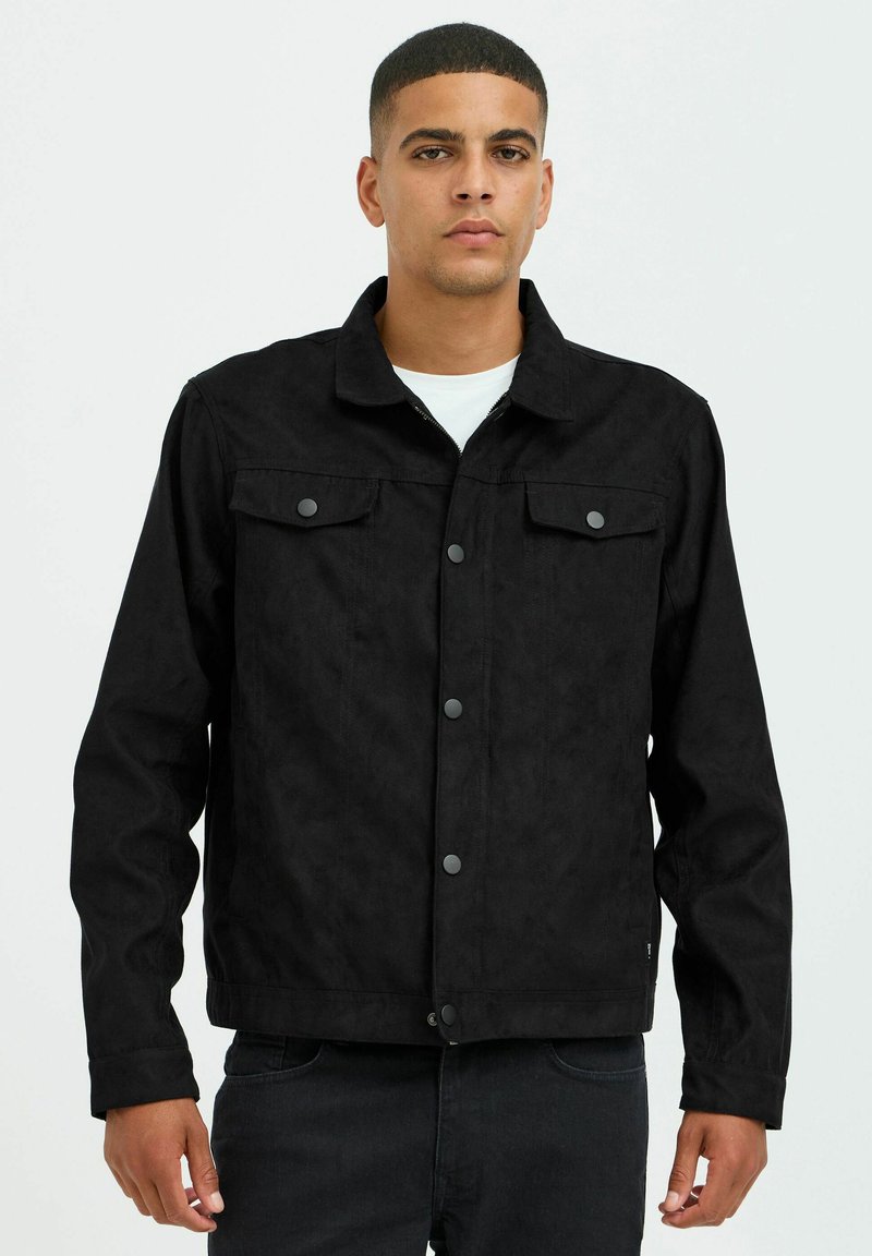 Veste en denim noir avec une finition texturée, comportant un col à pointes, une fermeture à boutons à l'avant, et deux poches sur la poitrine avec rabats.