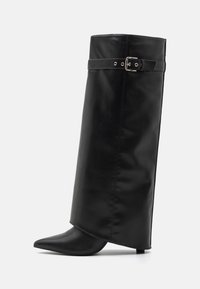 Bota de cuero negra con punta afilada y un caña alta y estructurada. Presenta un detalle de hebilla en el tobillo y un tacón cuadrado. Textura suave.