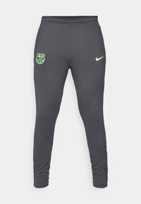 Grijze sportieve joggers met een aansluitend ontwerp, voorzien van een limoen groene Nike-logo en een Barcelona clubembleem op het linker bovenbeen. Rekbare stof.