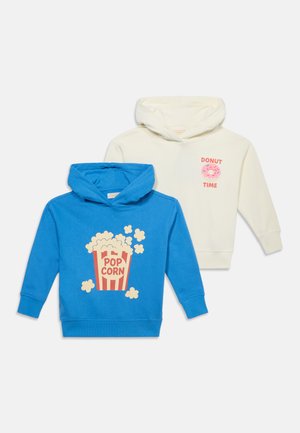 Deux sweats à capuche pour enfants, un bleu avec un motif popcorn, un blanc avec un donut rose et le texte "Donut Time".