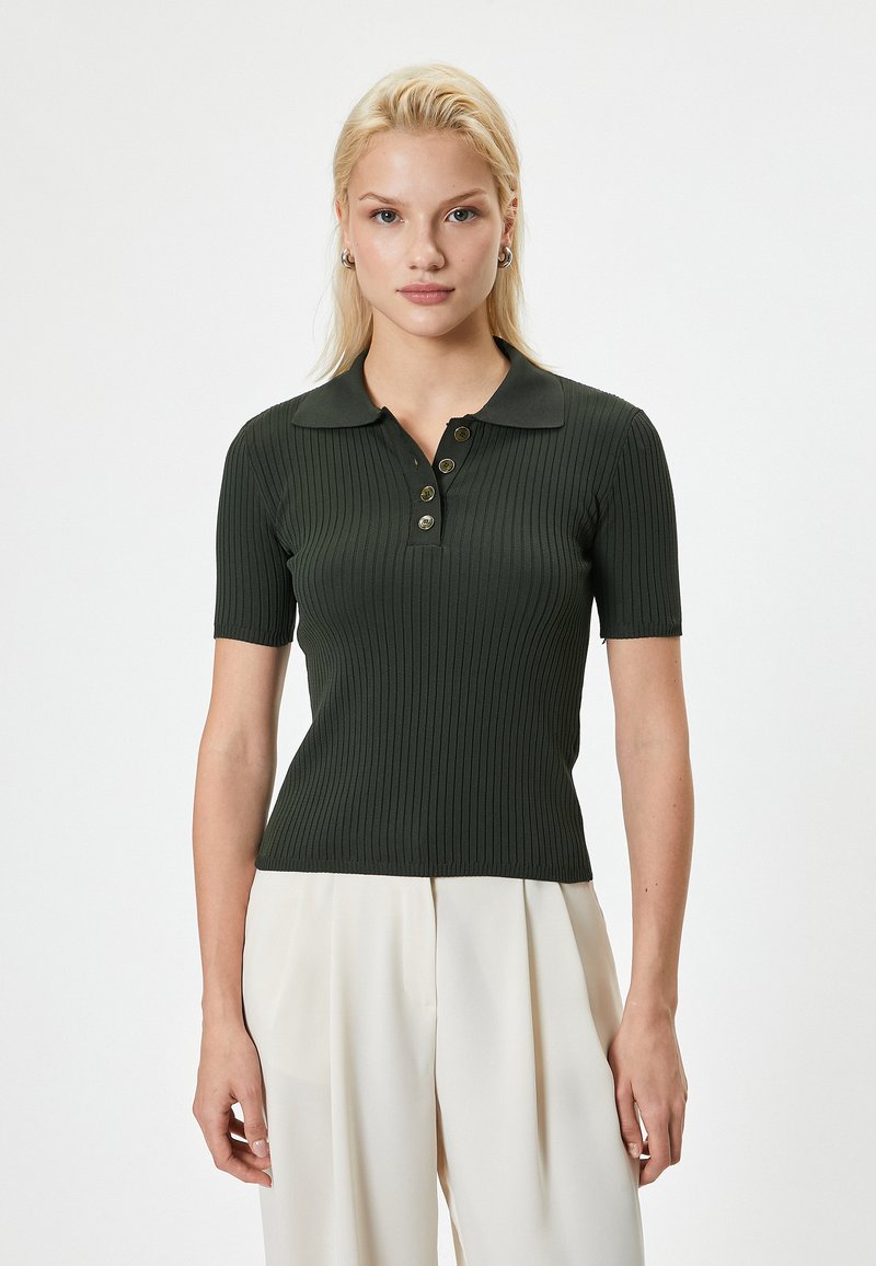 Polo shirt côtelé vert foncé à manches courtes, avec patte de boutonnage et col classique. Texture lisse avec une coupe ajustée.