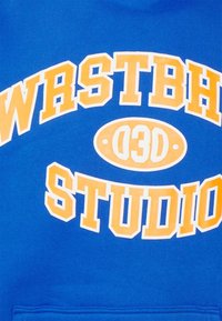 Blauer Hoodie mit großem gelbem und weißem Text "WRSTBH 03D STUDIO." Verfügt über eine glatte Textur und eine Kängurutasche.