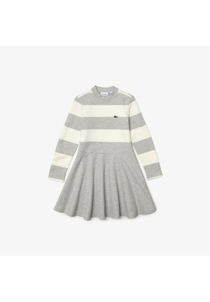 Grijze jurk met lange mouwen, witte horizontale strepen en een uitlopende rok. Heeft een geribbelde textuur en een klein groen logo op de borst.