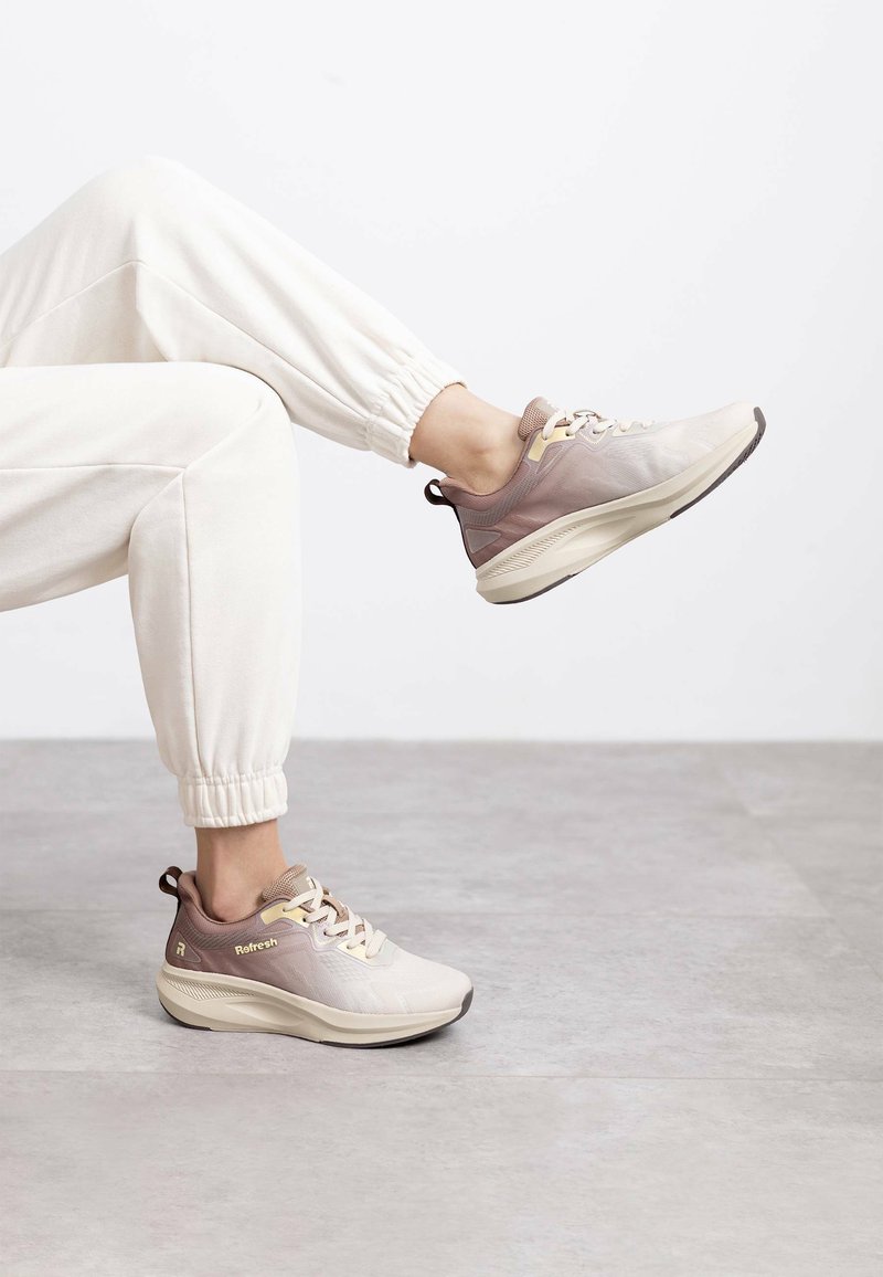 Zapatillas ligeras en tonos beige y malva, con un upper de malla texturizada, cuello acolchado y suela de goma en contraste con un diseño minimalista.