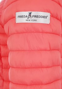 Koronkowa kurtka puchowa w kolorze koralowym z pikowanymi sekcjami, z metką na białym tle, na której znajduje się napis "FRIEDA FREDDIES NEW YORK".