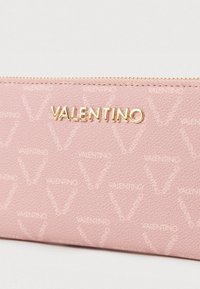 Portafoglio in pelle testurizzata rosa con logo dorato "VALENTINO", caratterizzato da un motivo ripetitivo sobrio e con chiusura a zip.