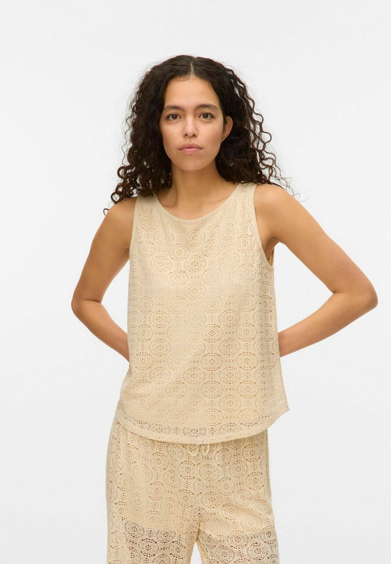 Beige mouwloos top met een haakpatroon van cirkelvormige motieven, gemaakt van lichtgewicht stof, met een ronde halslijn en een relaxte pasvorm.
