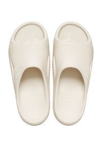 Jasno beżowe klapki typu slip-on z teksturowaną cholewką, zdobione wypukłymi żłobieniami oraz miękką, perforowaną wkładką dla wygody.
