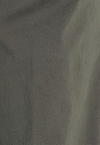 Miękka tkanina o ukośnym, delikatnym prążkowanym wzorze w stonowanych odcieniach szarości i zieleni, ukazująca subtelne gradienty światła i cienia.