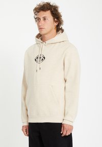 Beige katoenen hoodie met een vooraanstaande kangoeroezak, verstelbare trekkoordkap en een zwart grafisch logo op de borst. Slim fit ontwerp.